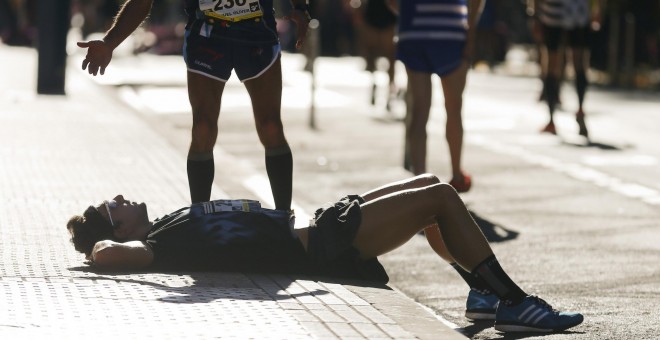 Un atleta descansa sobre la acera tras atravesar la línea de meta, durante la 51 edición de la carrera popular Behobia-San Sebastián, en la que participan 34.000 personas. EFE/Juan Herrero