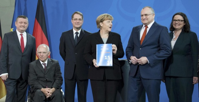 La canciller alemana Angela Merkel con el informe anual del Consejo Asesor de Economistas del Gobierno alemán, con su presidente Christoph Schmid a su izquierda. REUTERS/Stefanie Loos