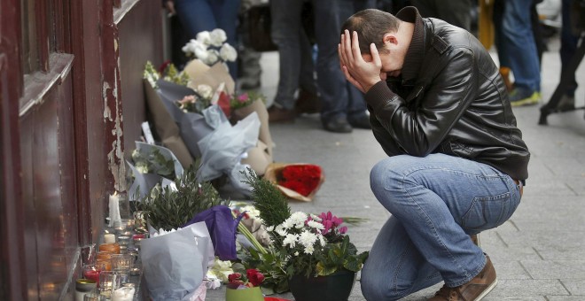 Un hombre se arrodilla en las afueras del restaurante Le Carillon  de París, uno de los objetivos de los ataques de los terroristas. - REUTERS