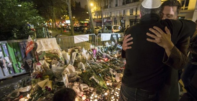 Dos hombres se abrazan junto a la sala Bataclan durante la vigilia en honor de las víctimas de los atentados. - EFE