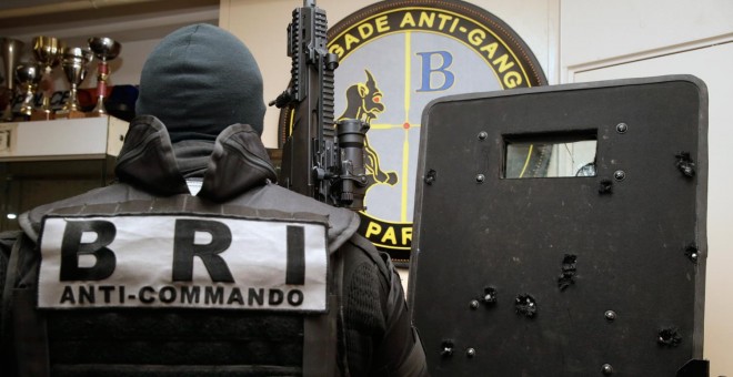 Agentes de la Policía y la Brigada de Intervención francesa (BRI) posan con el escudo, trufado de impactos de bala, que utilizaron para entrar en la sala Bataclan de París y liberar a los rehenes tomados por varios yihadistas.- AFP PHOTO / KENZO TRIBOUIL