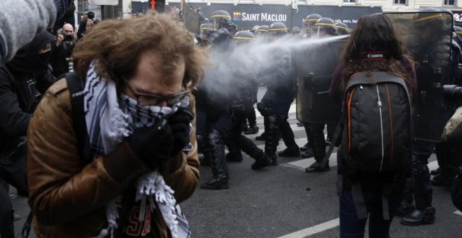 Un manifestante se tapa la boca para no inhalar el gas de la Policía durante la manifestación en París. /AFP