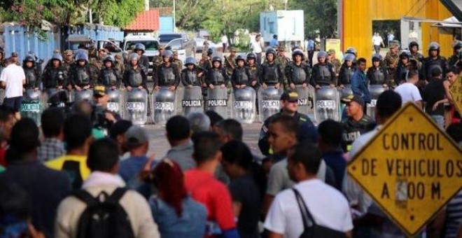 Una hilera de policías enfrente de manifestantes.