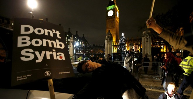 Un joven porta una pancarta contra los bombardeos en Siria frente al Parlamento británico. /REUTERS