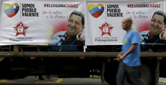 Un hombre pasa por Caracas junto a un camión con carteles electorales con la imagen del fallecido presidente velezolano Hugo Chávez. REUTERS / Marco Bello