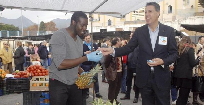 El presidente del grupo parlamentario del PP de Catalunya, Xavier Garcia Albiol, entrega un mantecado con propaganda electoral del PP a uno de los vendedores durante la visita que ha realizado hoy al mercadillo de las Albarizas de Marbella, acompañado por