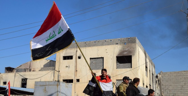 Un miembro de las fuerzas iraquíes sostiene una bandera en un complejo gubernamental en la ciudad de Ramadi. REUTERS/Stringer