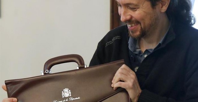 El líder de Podemos, Pablo Iglesias, muestra su nuevo maletín como miembro en el Congreso de los Diputados tras formalizar hoy su acta de diputado en la Cámara Baja. EFE/Zipi