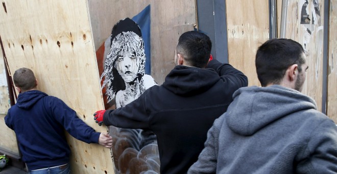 varios trabajadores retiran una tabla después de descubrir un nuevo mural de Banksy, frente a la embajada francesa en Londres.- REUTERS / Stefan Wermuth