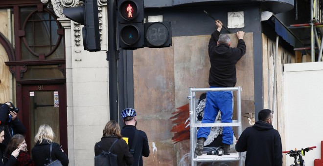 Un trabajador intenta quitar un nuevo mural de Banksy, frente a la embajada francesa en Londres. REUTERS / Stefan Wermuth