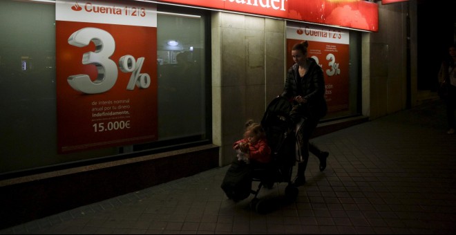 Una mujer con el carrito de su bebé pasa por delante de una oficina del Banco Santander. REUTERS/Andrea Comas
