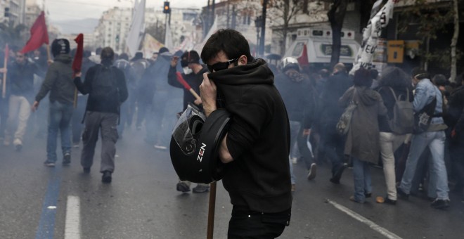 A protester covers his face to avoid breathing tear gas during clashes marking a 24-hour general strike against planned pension reforms in Athens, Greece, February 4, 2016. REUTERS/Alkis Konstantinidis