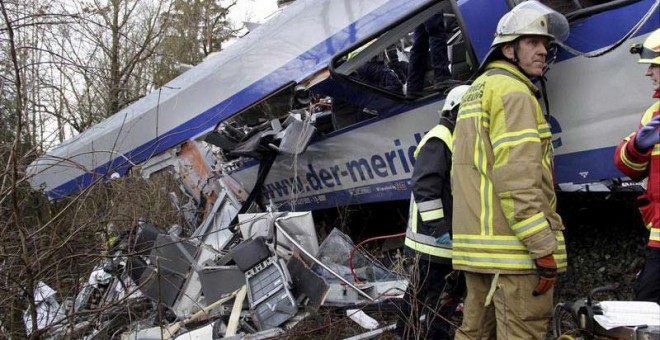 Un miembro de los equipos de rescate junto a los trenes accidentados. / EFE