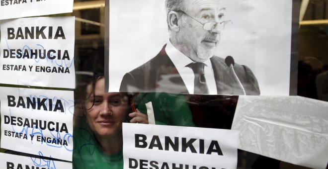 Una activista mira a través de una ventana desde el interior de la sucursal de Bankia en Madrid donde se ha llevado a cabo una protesta contra los desahucios. REUTERS/Andrea Comas