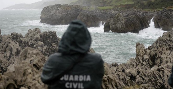 Un agente de la Guardia Civil supervisa la zona donde un pescador cántabro ha desaparecido. EFE/Pedro Puente Hoyos