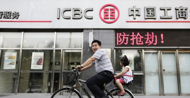 Un hombre pasa con su bicicleta por delante de una oficina del banco ICBC en Pekin. REUTERS