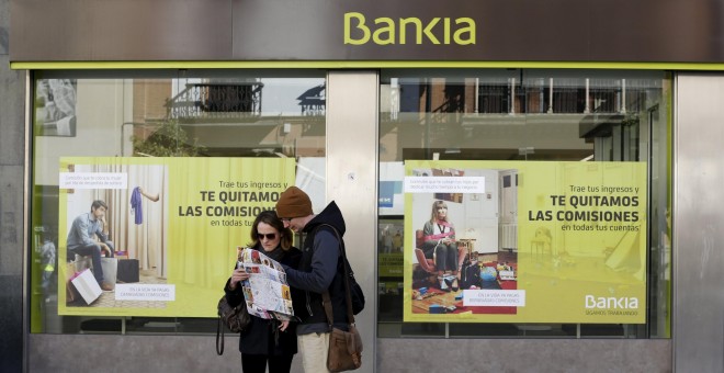 Dos turistas consultan un mapa frente a una oficina de Bankia en Sevilla. REUTERS/Marcelo del Pozo