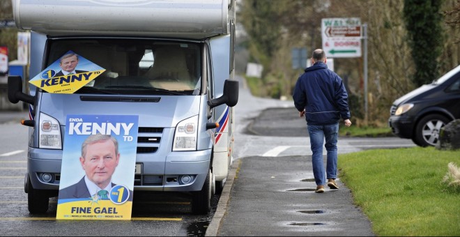 Un hombre camina junto a una autocaravana que muestra carteles del líder del partido Fine Gael (FG), el primer ministro irlandés Enda Kenny, en Castlebar en Irlanda. EFE/Aidan Crawley