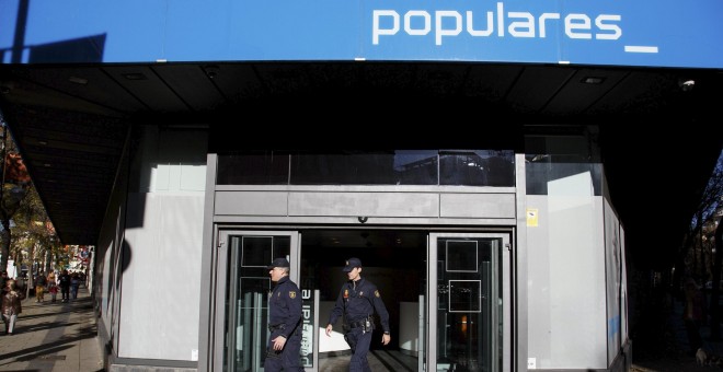 Dos agentes de Policía salen de la sede del PP en la madrileña calle de Génova, tras el registro realizado en diciembre de 2013 durante 14 horas en busca de documentación sobre el pago en B de las obras del edificio, en . REUTERS/Paul Hanna