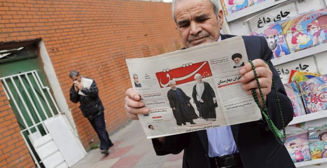 Un hombre sostiene un periódico iraní con una imagen del presidente Rohaní y del expresidente Rafsanjani bajo el título: 'Decisiva victoria de los reformistas'. - EFE