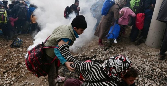 Una mujer trata de sacar a sus hijos de la zona donde la Policía macedonia ha dispersado los gases lacrimógenos. - AFP