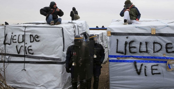 Agentes antidisturbios pasan entre los refugios levantados en la 'Jungla' de Calais. - REUTERS