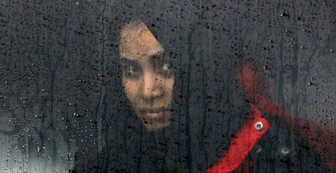 Una mujer mira por la ventana de un tren mientras espera poder abandonar el campo de Slavonski Brod. - REUTERS