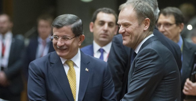 El primer ministro turco Ahmet Davutoglu (izda) se estrecha la mano con el presidente del Consejo Europeo Donald Tusk, durante la cumbre de los jefes de Estado. EFE/Olivier Hoslet