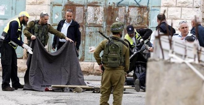 Soldados israelíes cubren el cuerpo sin vida de un palestino en Hebrón (Palestina) hoy, 24 de marzo de 2016.- EFE/Abed Al Hashlamoun
