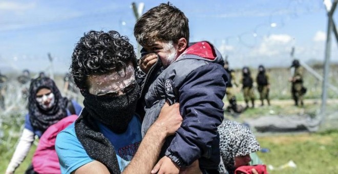 Una familia trata de huir de los gases lacrimógenos lanzados por la Policía macedonia. - REUTERS