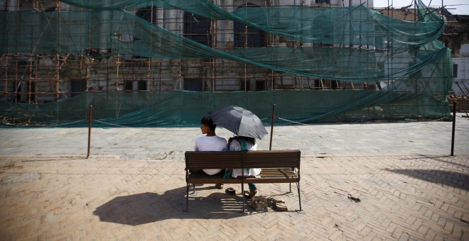 Personas sentadas frente a la Plaza Basantapur Durbar dañada. REUTERS/Navesh Chitrakar