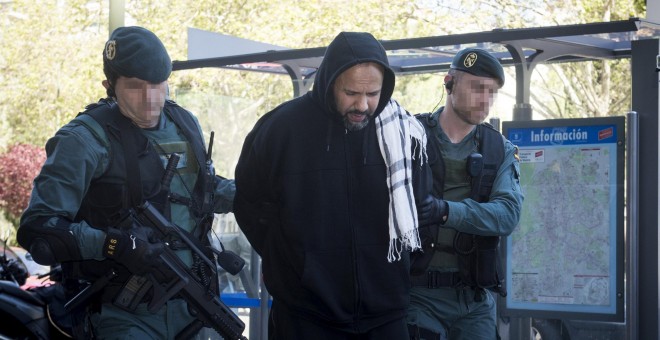 Uno de los cuatro detenidos en Madrid como presuntos integrantes de una organización encargada de la captación y adoctrinamiento de yihadistas es conducido por la Guardia Civil a uno de los registros. EFE/Luca Piergiovanni