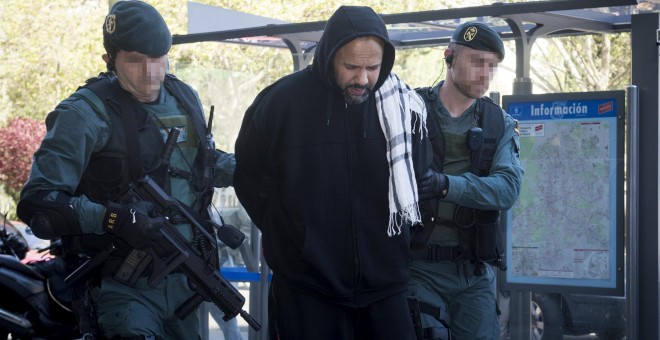 Uno de los cuatro detenidos en Madrid como presuntos integrantes de una organización encargada de la captación y adoctrinamiento de yihadistas es conducido por la Guardia Civil a uno de los registros. EFE/Luca Piergiovanni