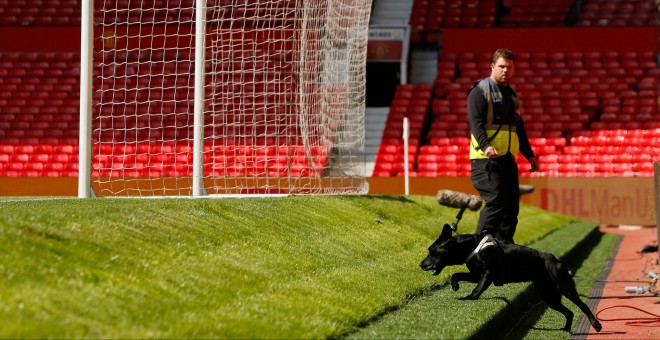 Un perro y su guía inspeccionan el estadio del Manchester United después de los miembros de seguridad ordenaran evacuar el estado por la presencia de un paquete sospechoso. REUTERS