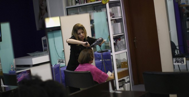 Una peluquera atiende a una cliente en su establecimiento de Madrid. REUTERS