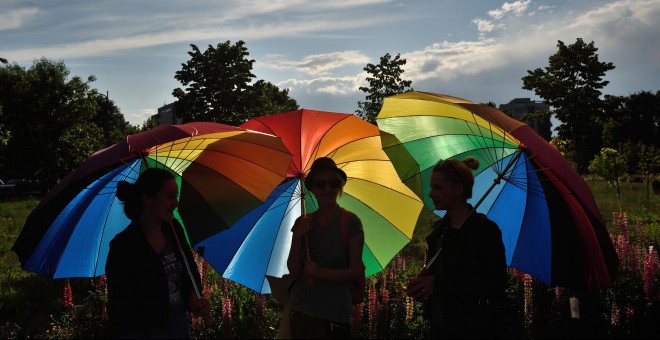 Personas sostienen paraguas arco iris para celebrar el Día Internacional contra la Homofobia frente al edificio del Parlamento rumano en Bucarest. DANIEL MIHAILESCU / AFP