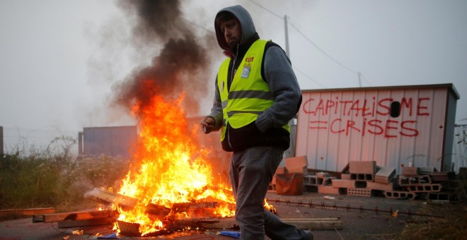Un miembro del sindicato francés se coloca cerca de una barricada para bloquear la entrada del depósito de la empresa SFDM cerca de la refinería de petróleo en Donges , Francia.- REUTERS / Stephane Mah