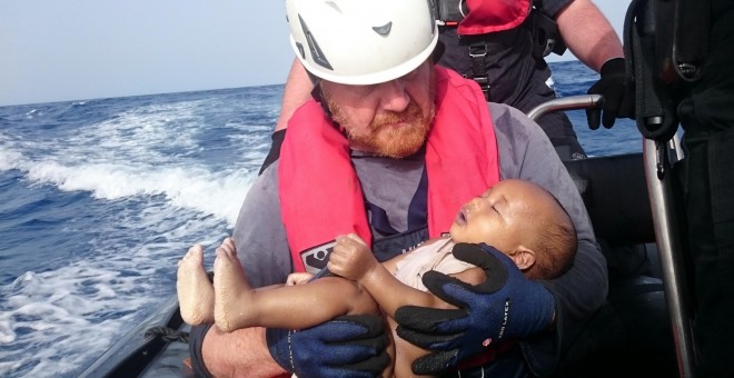 Un cooperante alemán de la organización humanitaria Sea-Watch sostiene el cuerpo de un bebé recogido del mar después de que el barco de refugiados en el que el viajaba naufragase en el Mediterráneo. REUTERS