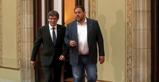 El presidente de la Generlitat, Carles Puigdemont, y el vicepresidente, Oriol Junqueras (d), salen del despacho de presidencial en el Parlament tras la reunión que han mantenido con los diputados de la CUP, Anna Gabriel y Joan Garriga, en la que diputados