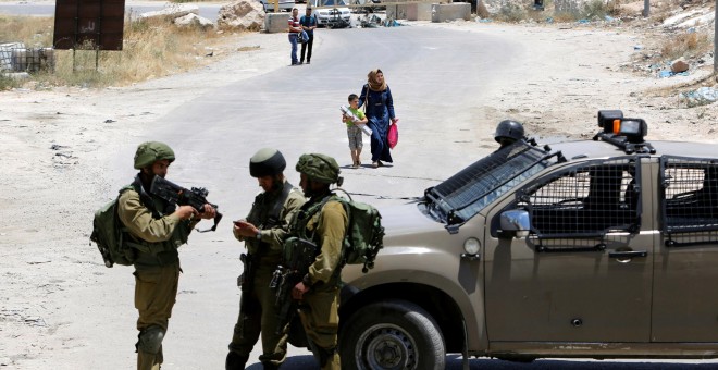 Soldados israelíes vigilan la entrada a la ciudad palestina de Yatta. REUTERS/Mussa Qawasma