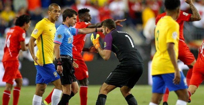 Alisson y Miranda, jugadores brasileños, protestan al árbitro el gol con la mano de Perú. EFE/LISA HORNAK