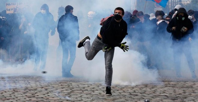 Un joven lanza un objeto a las fuerzas de seguridad en París. / PHILIPPE WOJAZER (REUTERS)