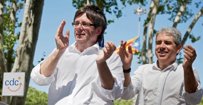 El cabeza de lista de CDC, Francesc Homs (d), y el presidente de la Generalitat, Carles Puigdemont (i), saludan a los asistentes tras la comida celebrada con motivo del acto de final de campaña de CDC en Girona celebrado en el Parc de la Devesa de Girona