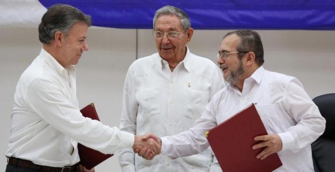 De izquierda a derecha, Juan Manuel Santos, presidente de Colombia, estrecha la mano del líder guerrillero Rodrigo Londono, más conocidad por su nombre de guerra, 'Timochenko'. Todo ello ante el presidente de Cuba, Raúl Castro. / REUTERS