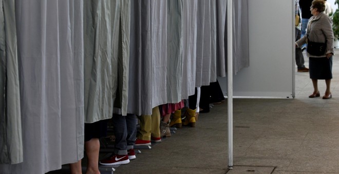 Varias personas en las cabinas preparan sus votos para el 26-J. REUTERS/Eloy Alonso