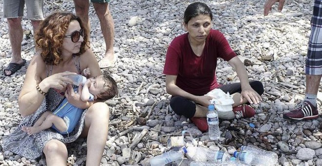 Una mujer da un biberón a un bebé en la isla de Lesbos (Grecia). EFE/Stratis Tsoulelis