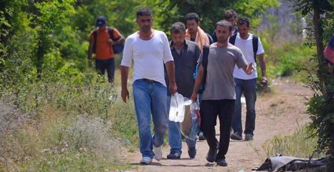 Varias personas caminan junto a un refugio temporal serbio en la frontera con Hungría. / EDVARD MOLNAR (EFE)
