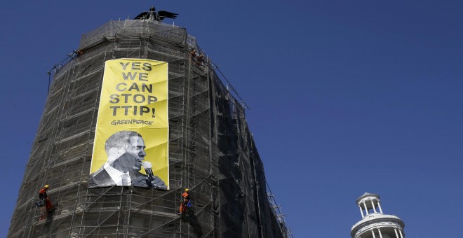 Activistas de Greenpeace cuelgan una pancarta con la imagen del presidente Barack Obama en la que se puede leer 'Sí podemos parar el TTIP', en el edificio Metrópolis de la Gran Vía la calle en Madrid. REUTERS/Javier Barbancho