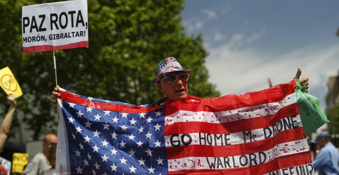 Un manifestante sostiene una bandera estadounidense con consignas durante una manifestación contra la visita del presidente Barack Obama en Madrid. REUTERS/Javier Barbancho