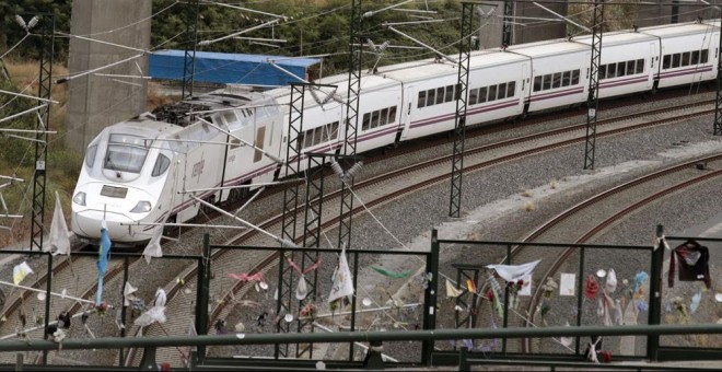 Un tren Alvia similar al accidentado en Angrois, pasa por la curva donde todavía permanecen objetos colocados en memoria de las 80 víctimas mortales. EFE